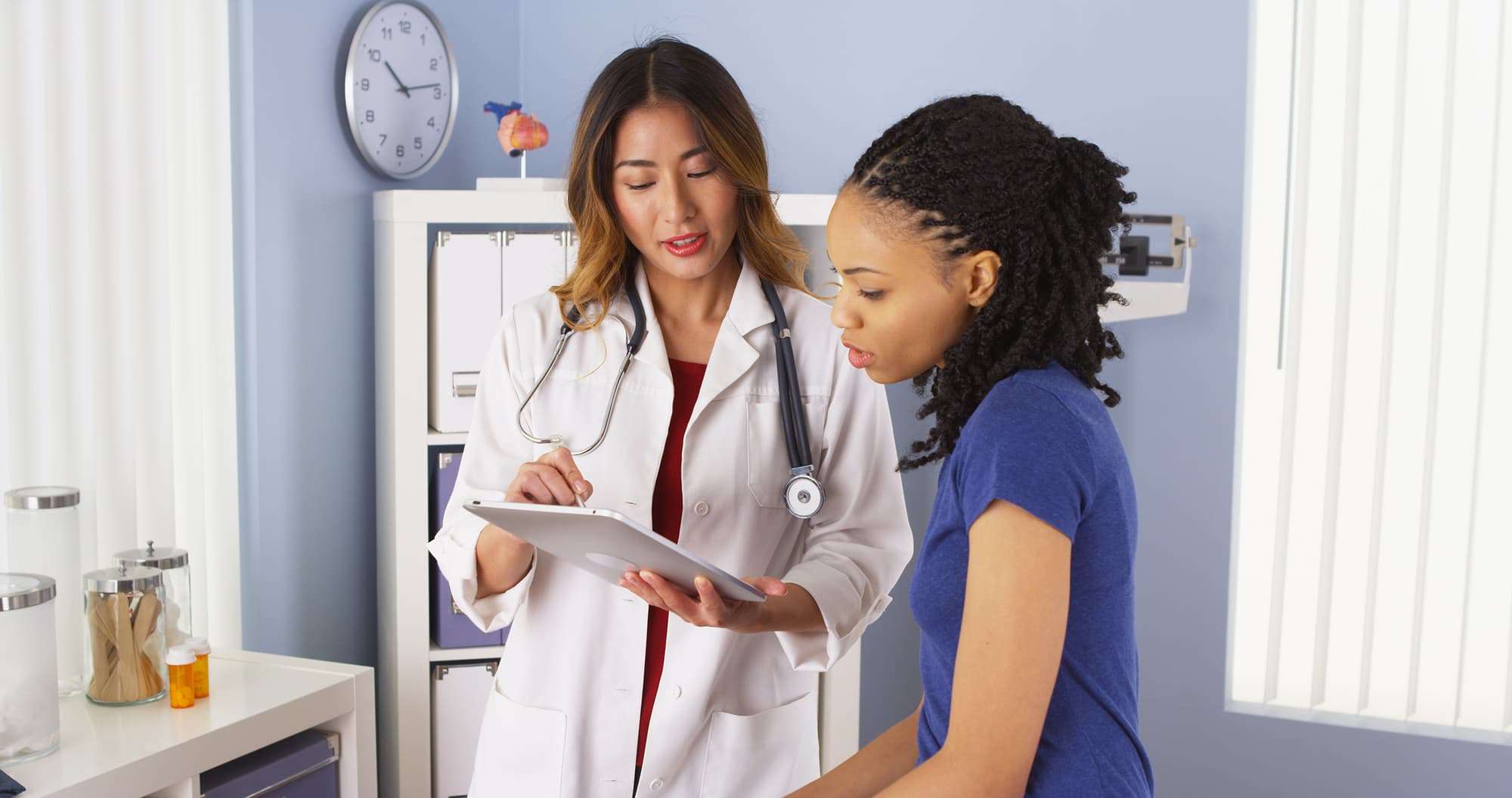 A medical professional reviewing test results with a patient in a doctor's office.