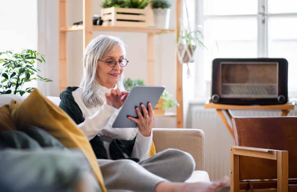 Portrait Of Senior Woman Sitting Indoors On Sofa At Home