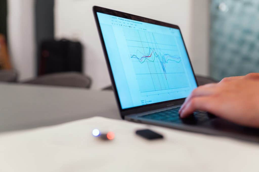 Hands typing on laptop with a line graph on screen