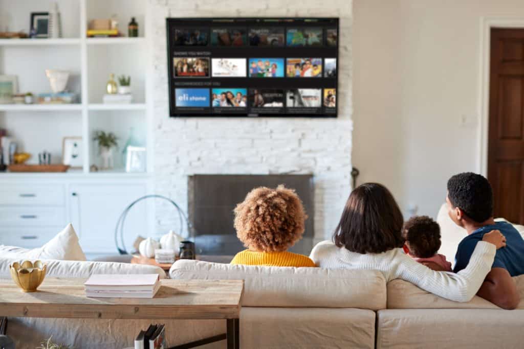 Four family members sit on a couch and watch TV