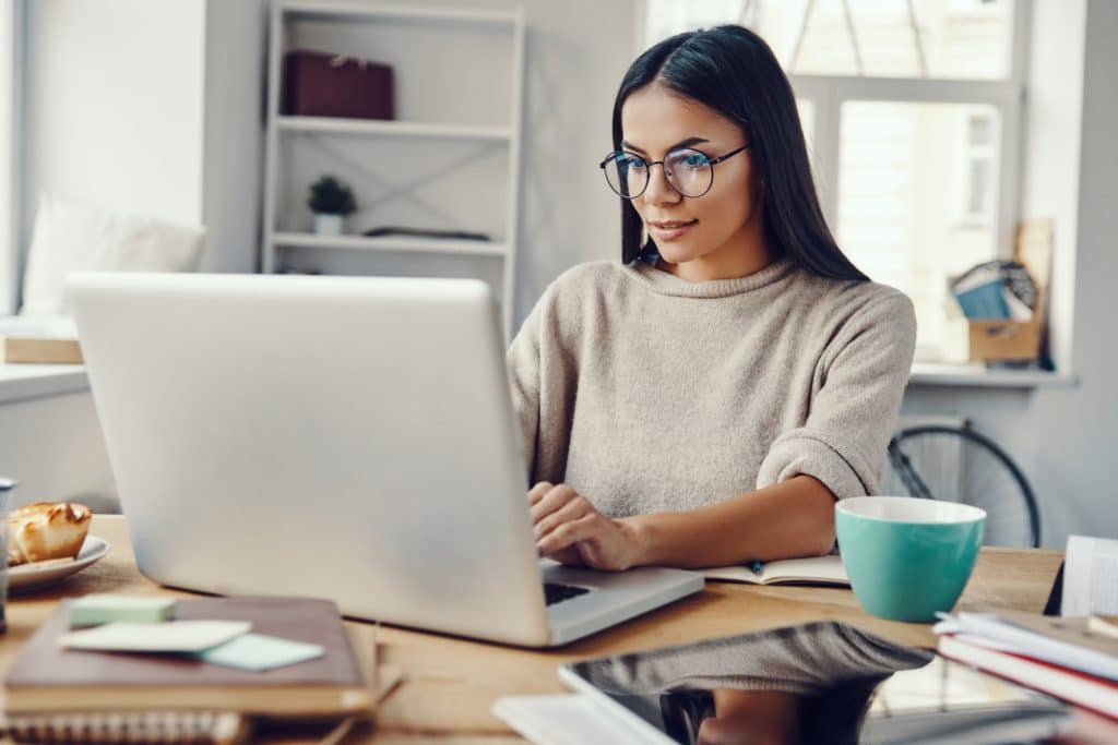 Woman wearing glasses typing on laptop