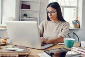 Woman wearing glasses typing on laptop